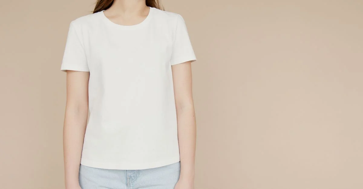 Mockup de una mujer en una camiseta blanca y jeans sobre un fondo beige, ideal para branding de moda.