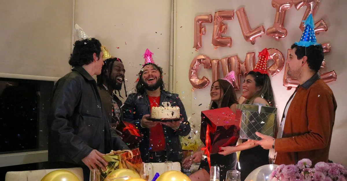 Una fiesta de cumpleaños alegre con amigos, pastel y confeti en interiores.