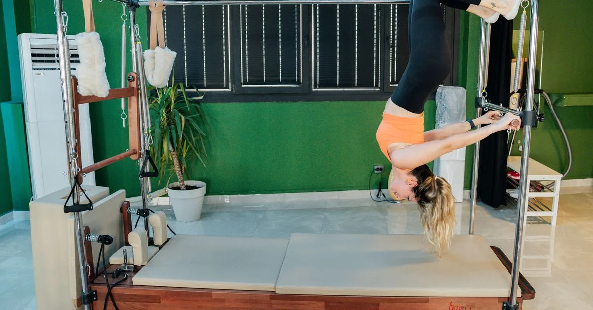 Mujer practicando ejercicio de pilates reformer en un moderno estudio de fitness