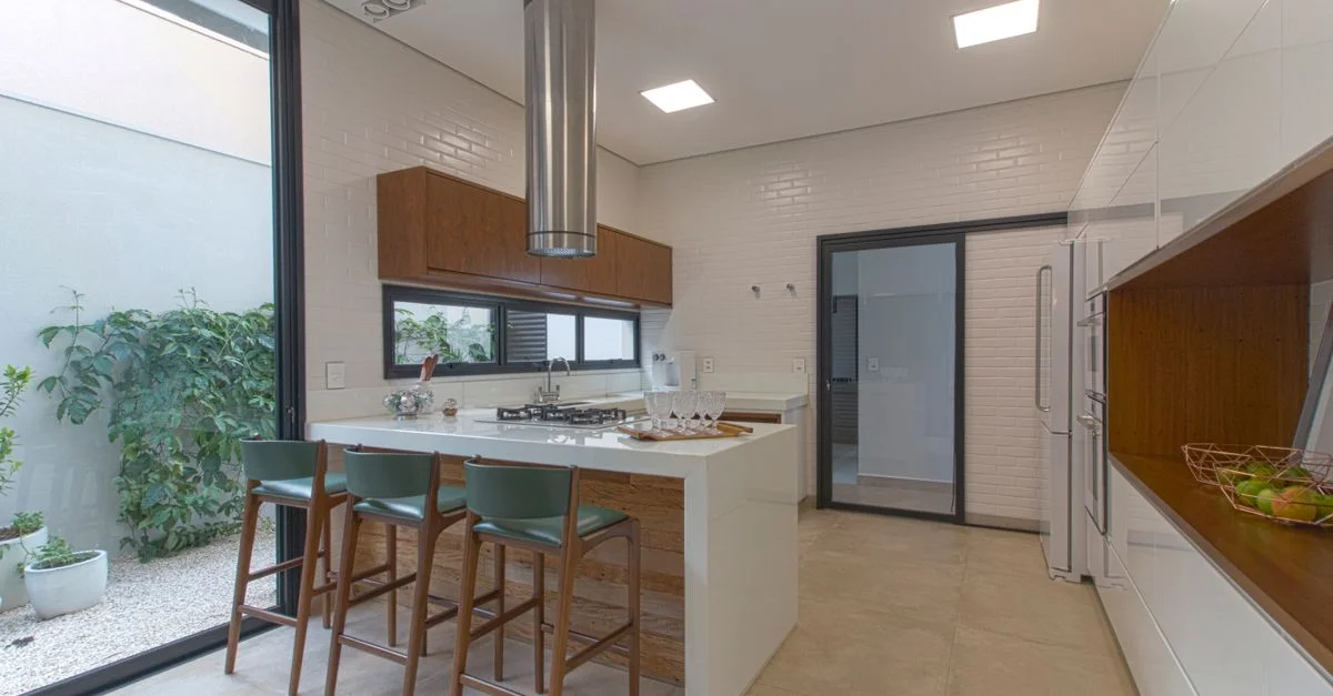Cocina moderna con paredes de ladrillo blanco, decoración de madera y taburetes de bar.