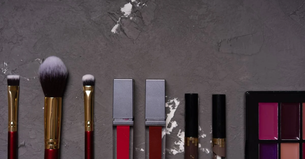 Toma de alta calidad de varios pinceles de maquillaje y cosméticos sobre un fondo texturizado.