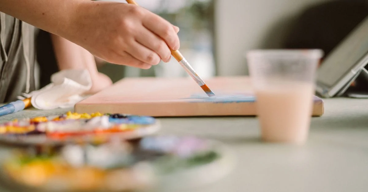 Artista aplicando pintura azul en el lienzo en un estudio en casa iluminado por el sol. Ambiente de espacio creativo.