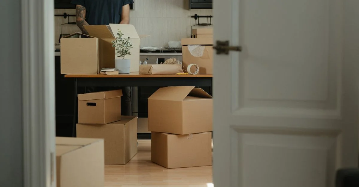 Persona desempacando cajas de cartón en una cocina moderna durante una mudanza.