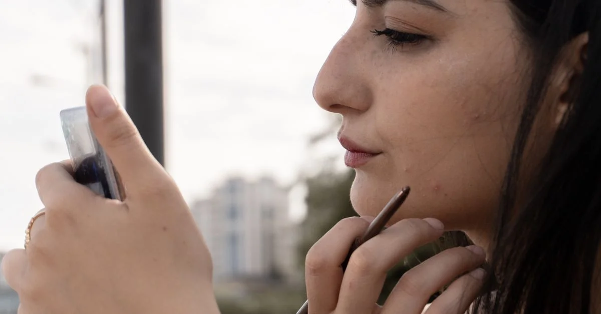 Perfil de una joven que se aplica maquillaje con delicadeza al aire libre en Bakú, Azerbaiyán.