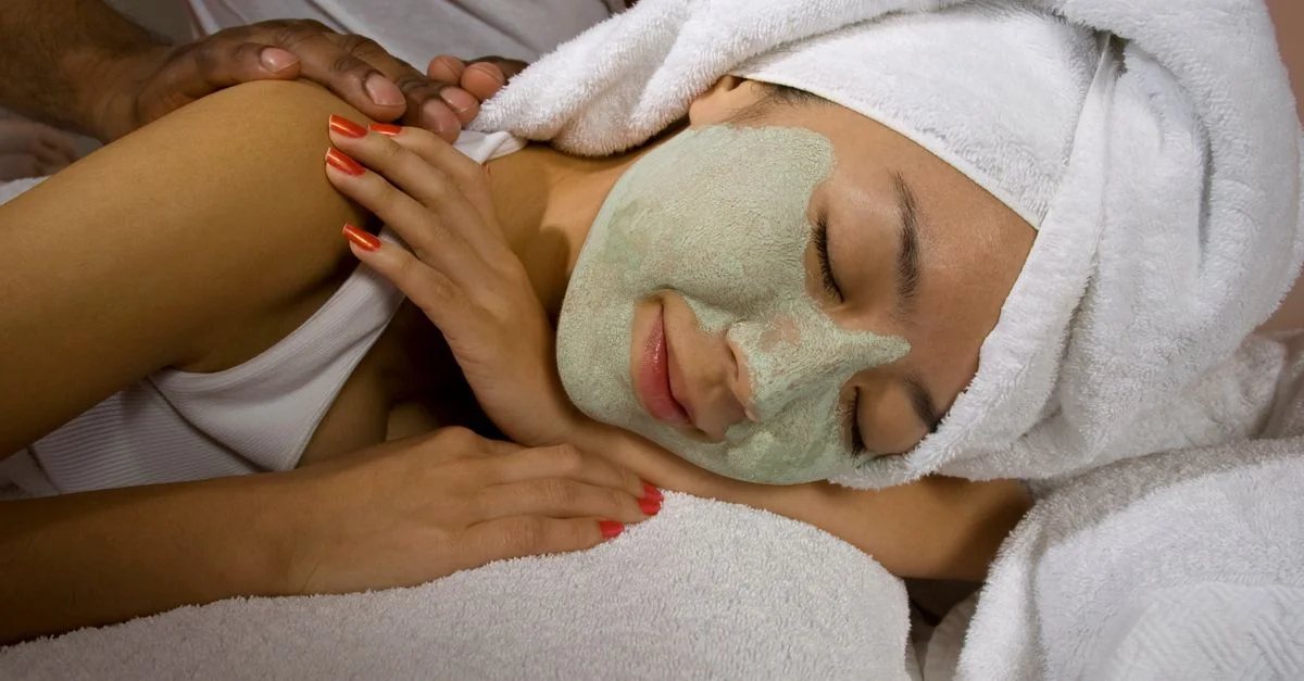 Una mujer disfrutando de una máscara facial rejuvenecedora y un masaje en un spa para relajación y cuidado de la piel.