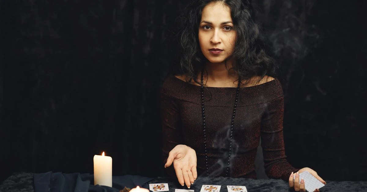 Una mujer se dedica a una lectura de cartas del tarot rodeada de velas, evocando una atmósfera mística.