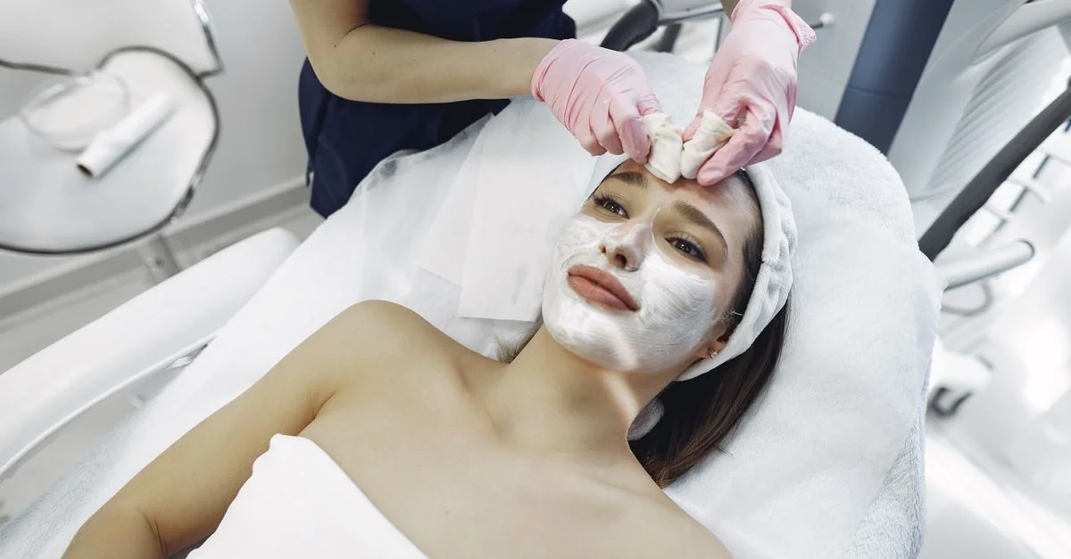 Tratamiento facial relajante en spa con cosmetólogo aplicando máscara a una cliente en interiores.