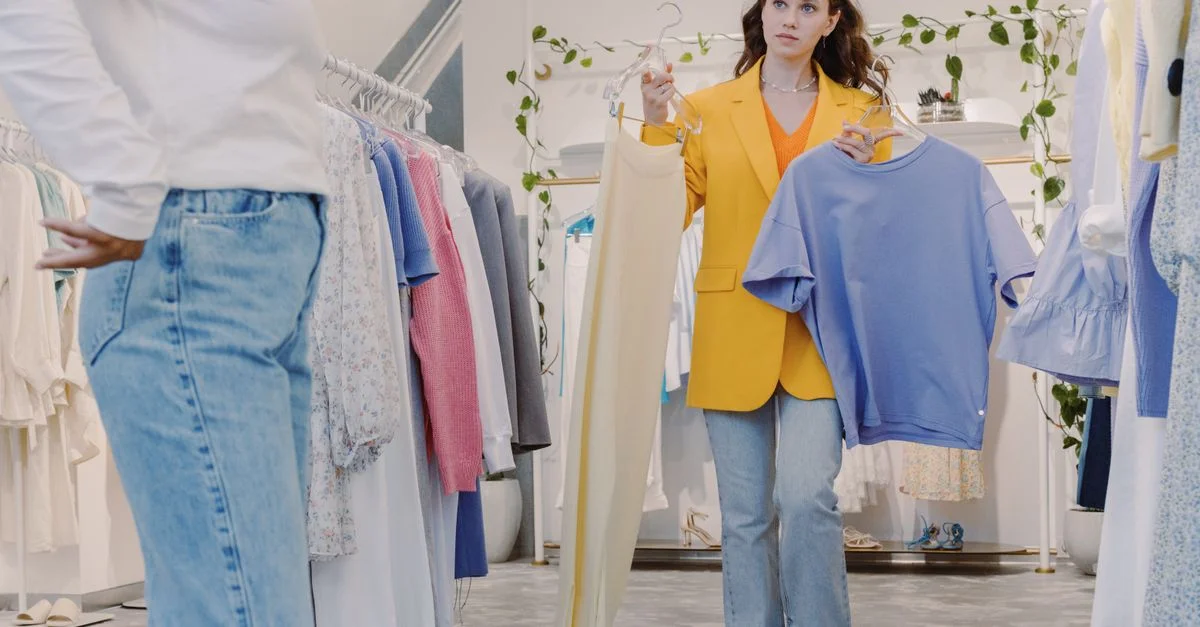Mujer comprando en una boutique sosteniendo ropa para probar en una tienda de moda moderna.
