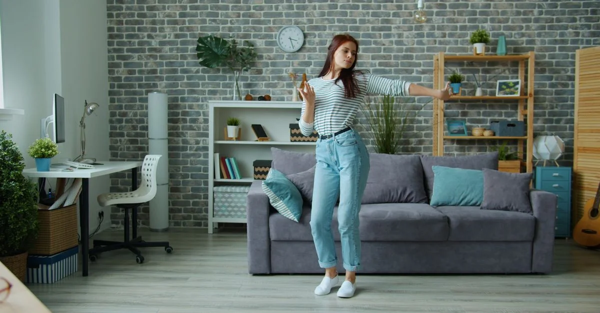 Una mujer disfruta bailando en una elegante sala de estar con decoración moderna.