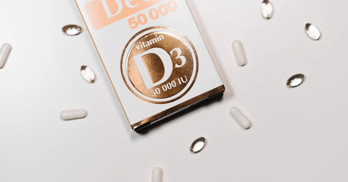 Toma plana de la caja de suplemento de Vitamina D3 y cápsulas sobre un fondo claro.