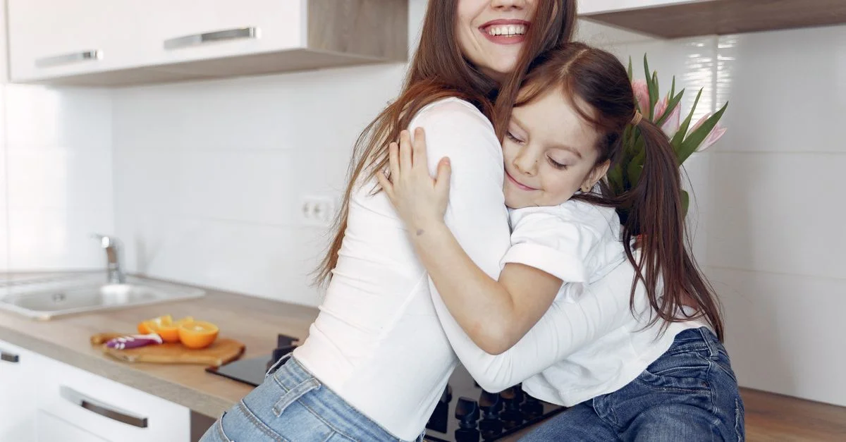 Un momento alegre de una madre y una hija abrazándose en una cocina moderna.