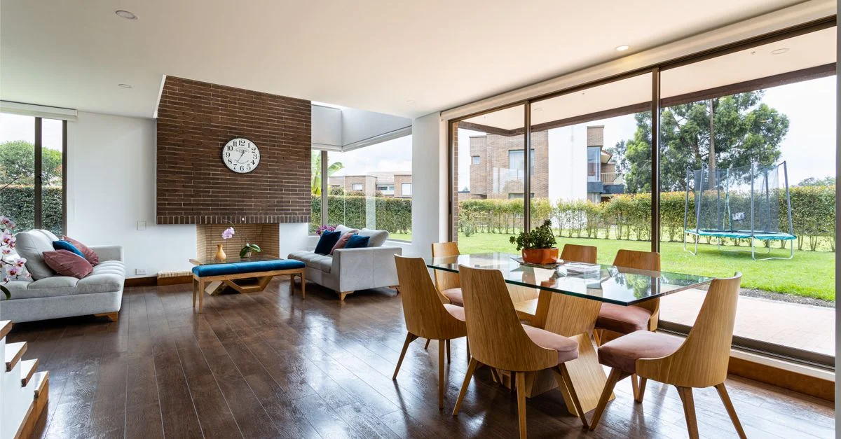 Amplia área de estar y comedor con ventanas de vidrio y muebles modernos.
