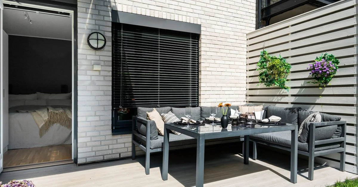 Terraza contemporánea con muebles elegantes y vegetación exuberante, ideal para relajarse en verano.