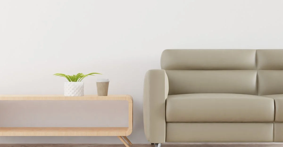 Sala de estar moderna con un sofá beige, planta y taza de café sobre una mesa de madera elegante.