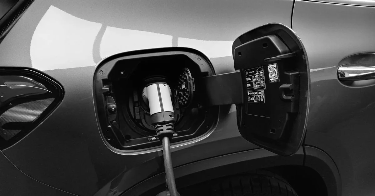 Imagen en blanco y negro en primer plano de un vehículo eléctrico cargando en una estación.