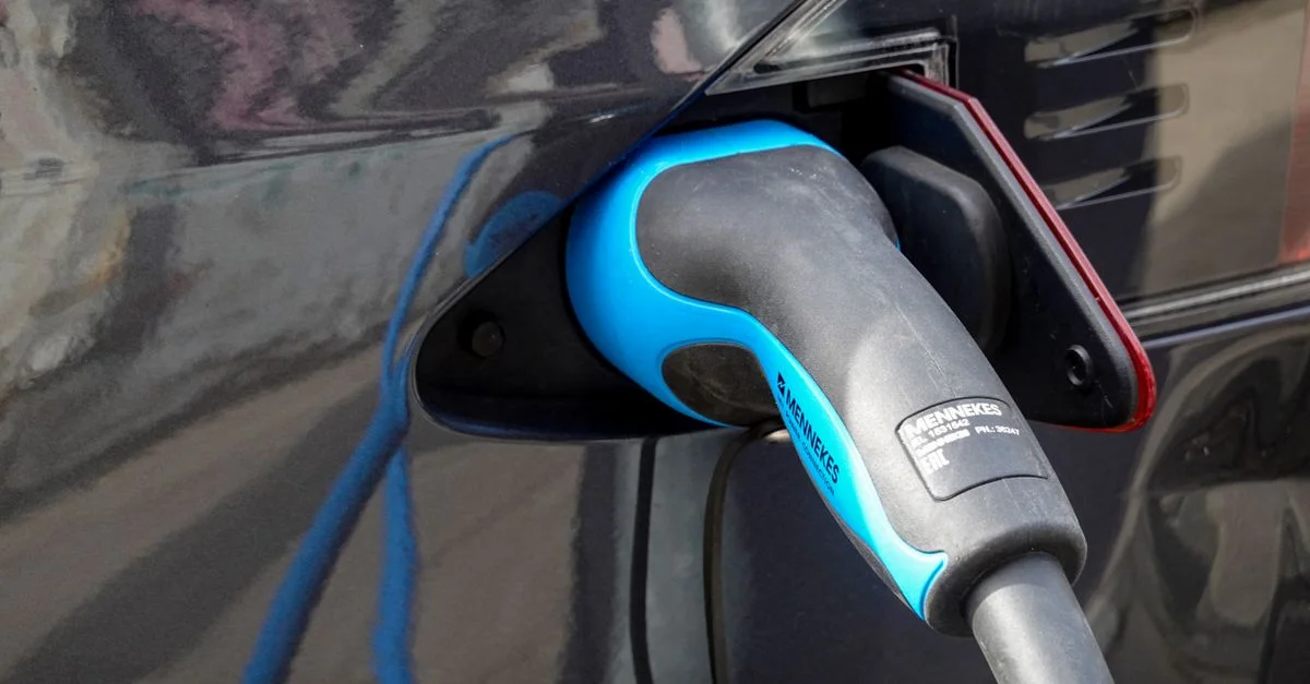 Primer plano de un vehículo eléctrico siendo cargado con un conector Mennekes EV.