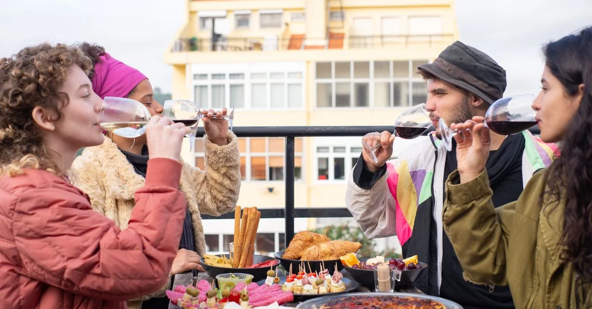 Grupo de amigos disfrutando de vino y aperitivos en una terraza portuguesa.