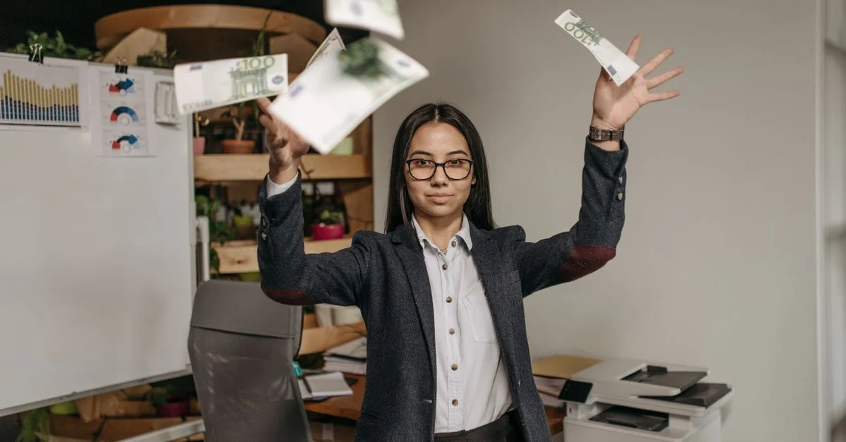 Mujer de negocios segura en atuendo formal lanzando billetes de euro en un entorno de oficina moderno.