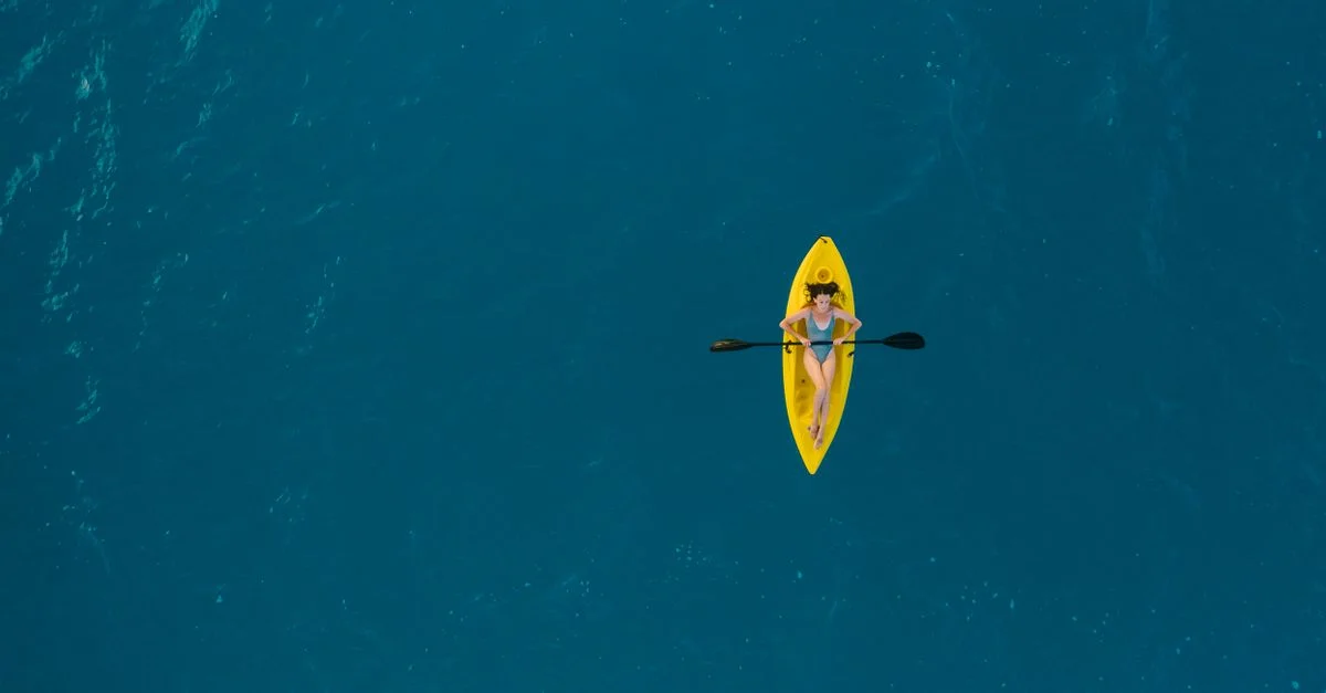 Vista aérea de una mujer haciendo kayak en las claras aguas turquesas de Bacalar, México.