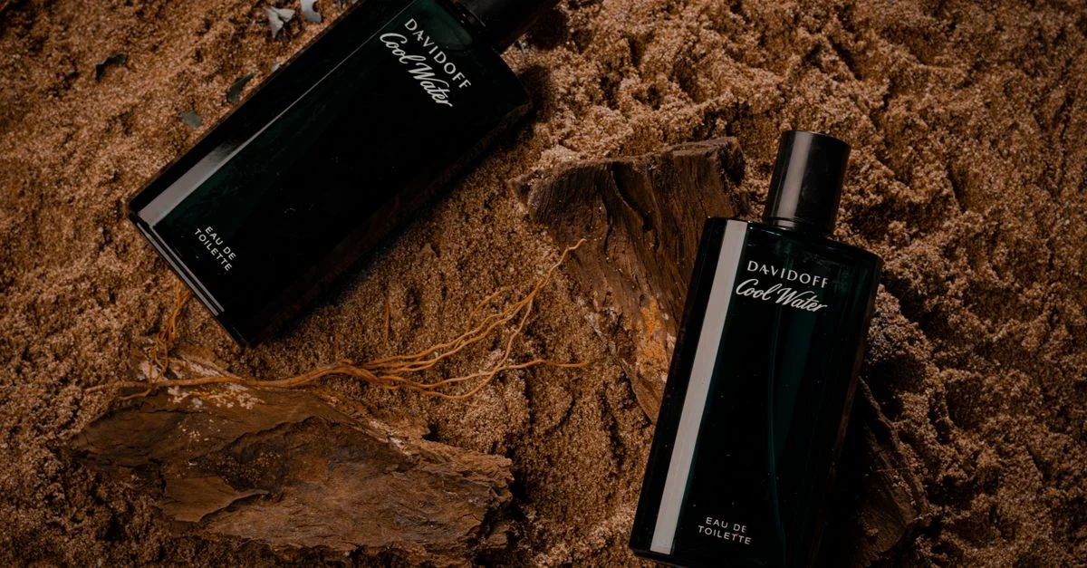 Primer plano de botellas de perfume elegantes sobre fondo de arena, ideal para fotografía de productos.