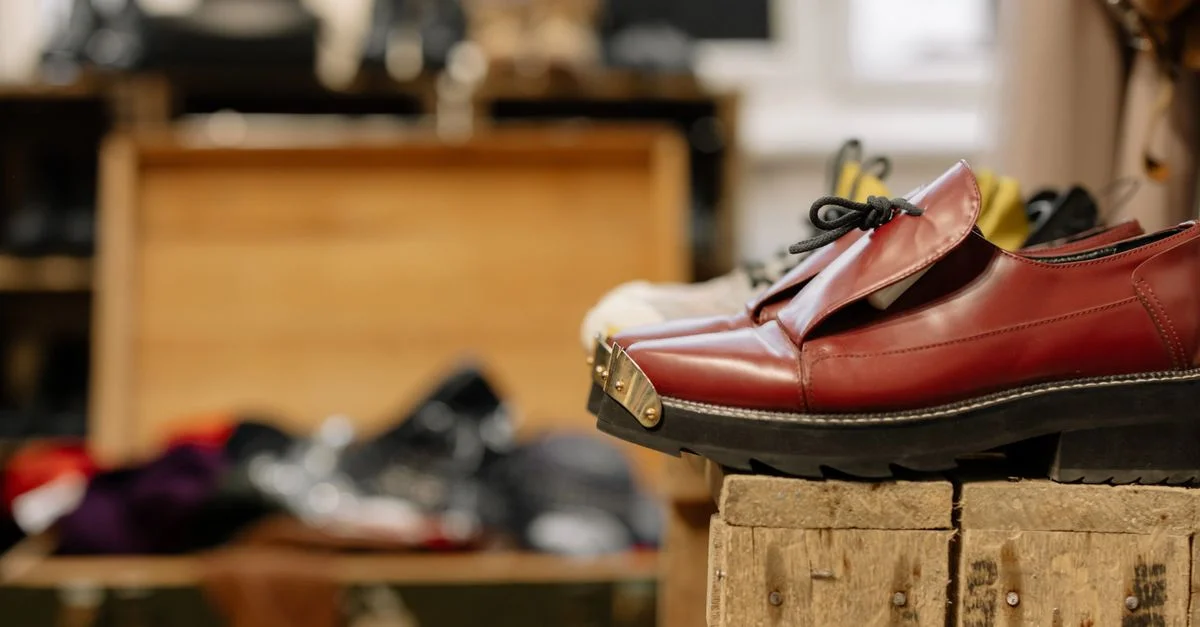 Elegantes zapatos de cuero rojo exhibidos en una caja de madera rústica, perfectos para temas de moda vintage.