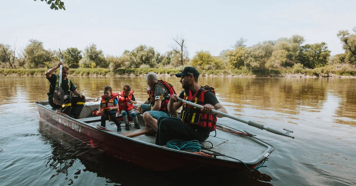 Familia disfrutando de un día pacífico en un lago en un bote de remos con chalecos salvavidas.