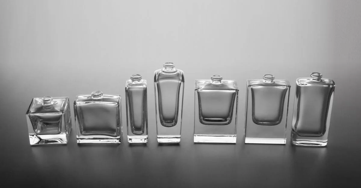 Una exhibición sofisticada de botellas de perfume de cristal vacías dispuestas sobre un fondo neutro, que epitomiza la elegancia minimalista.