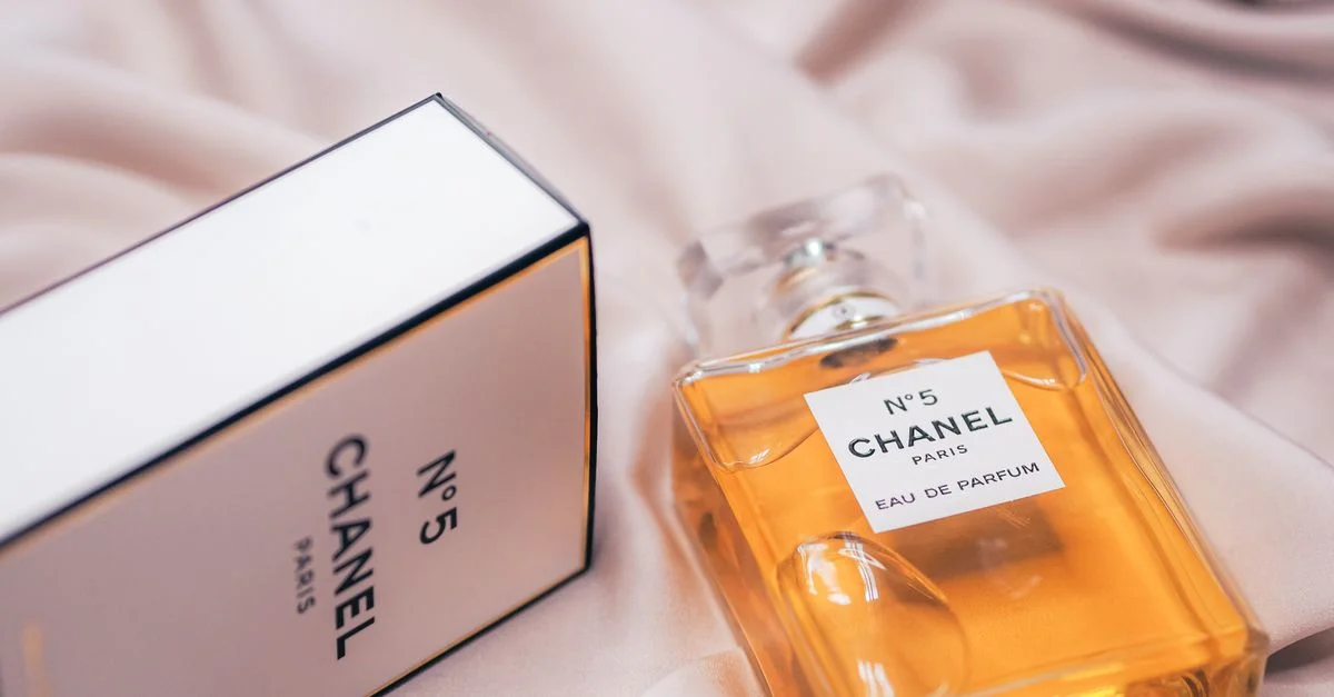 Primer plano de la botella y la caja del perfume Chanel No.5 sobre una tela suave en París.