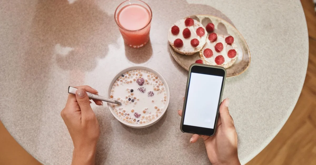 Un acogedor desayuno con cereales, tostadas y la pantalla de un smartphone a la vista.