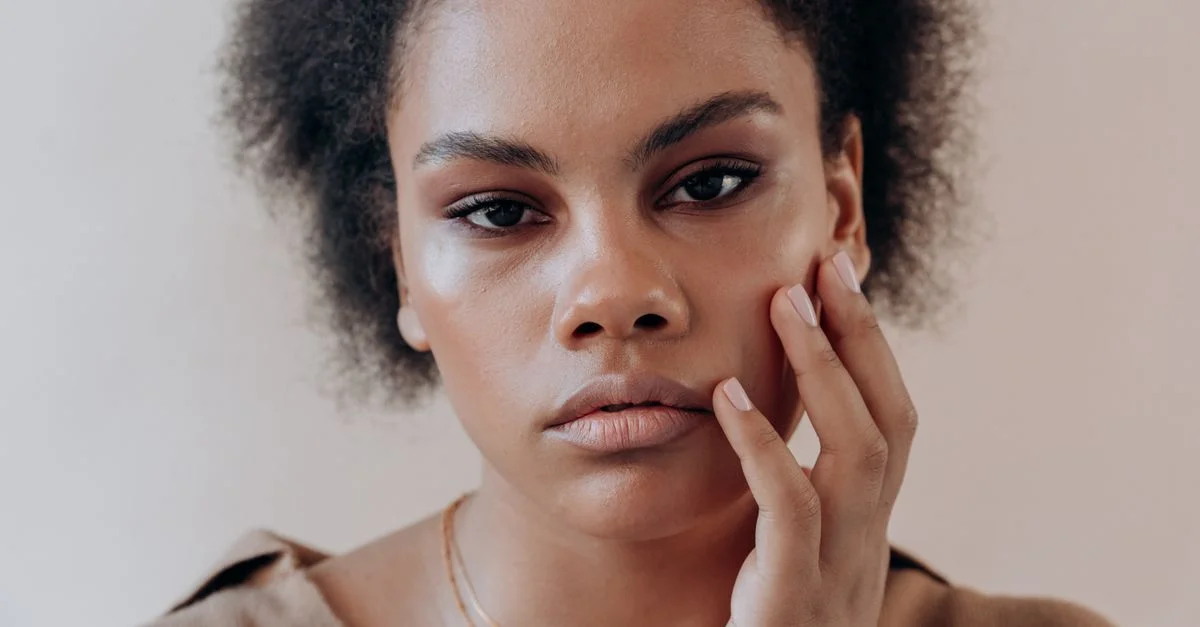 Retrato en primer plano de una mujer con cabello afro, expresando introspección reflexiva.