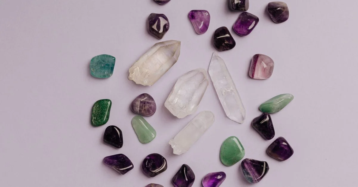 Una colección de piedras preciosas variadas, incluyendo amatista, jade y cuarzo, dispuestas en un plano.