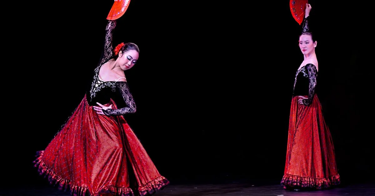 Dos bailarinas de flamenco se presentan con abanicos rojos en un elegante espectáculo.