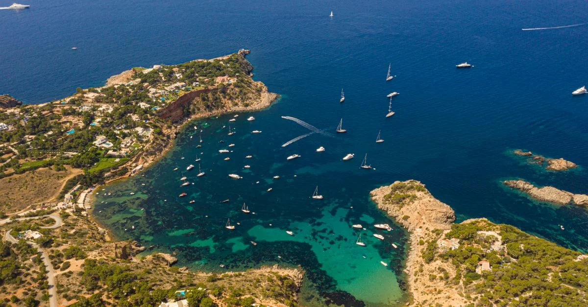 Impresionante vista aérea de la costa de Ibiza con aguas turquesas y yates.