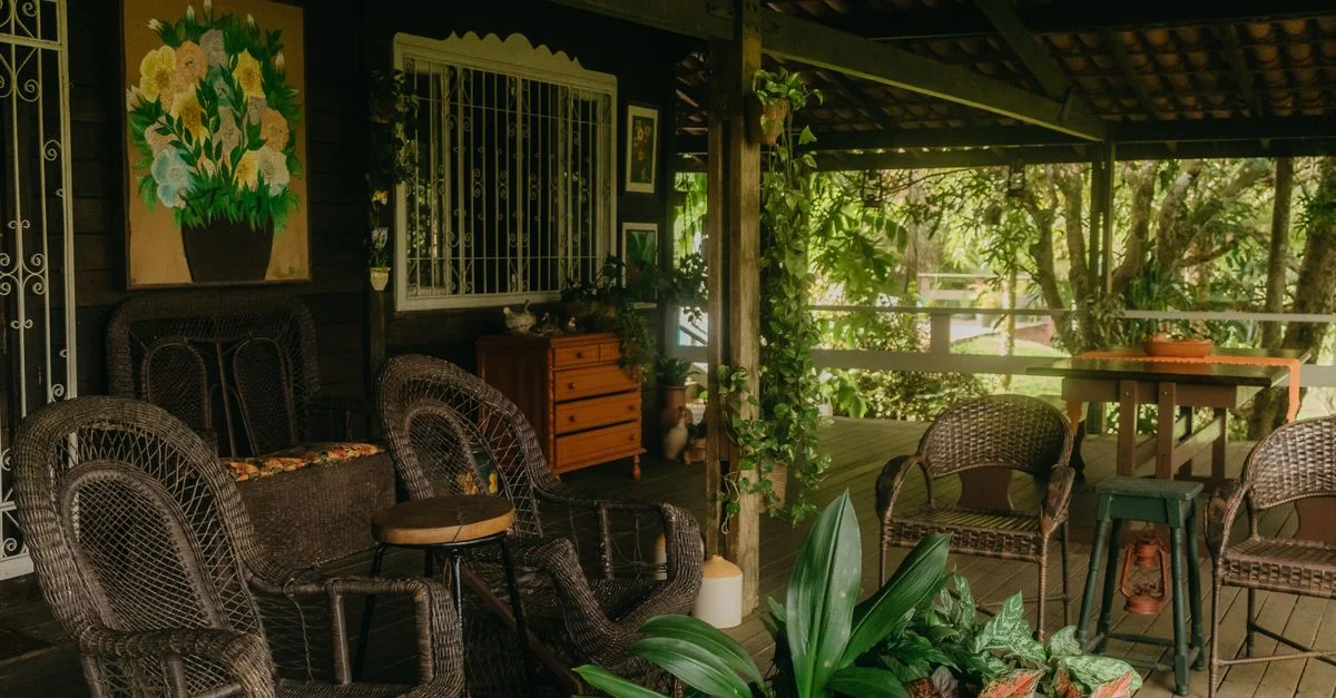 Un tranquilo patio al aire libre con muebles de mimbre, plantas exuberantes y un ambiente acogedor.