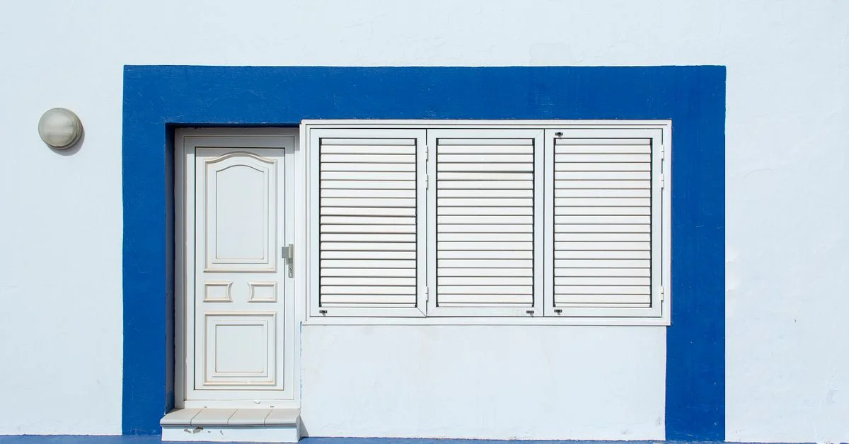 Fachada de casa blanca y azul con puerta y contraventanas en Lanzarote, España.