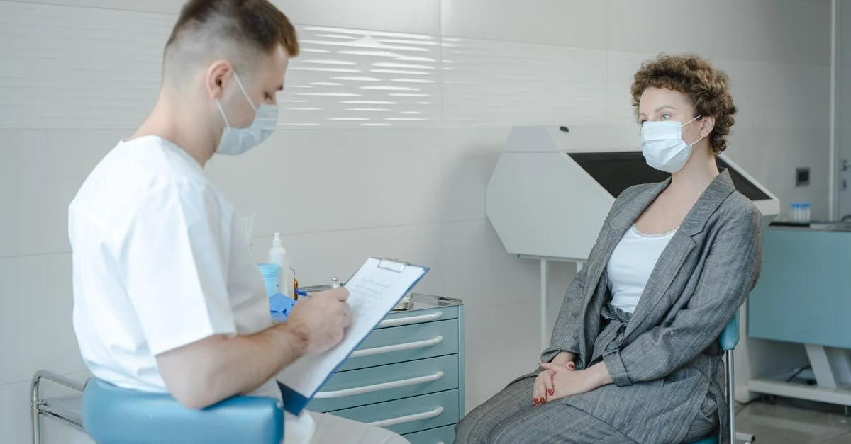 Un médico con mascarilla consulta a un paciente en una clínica, reflejando la nueva normalidad.